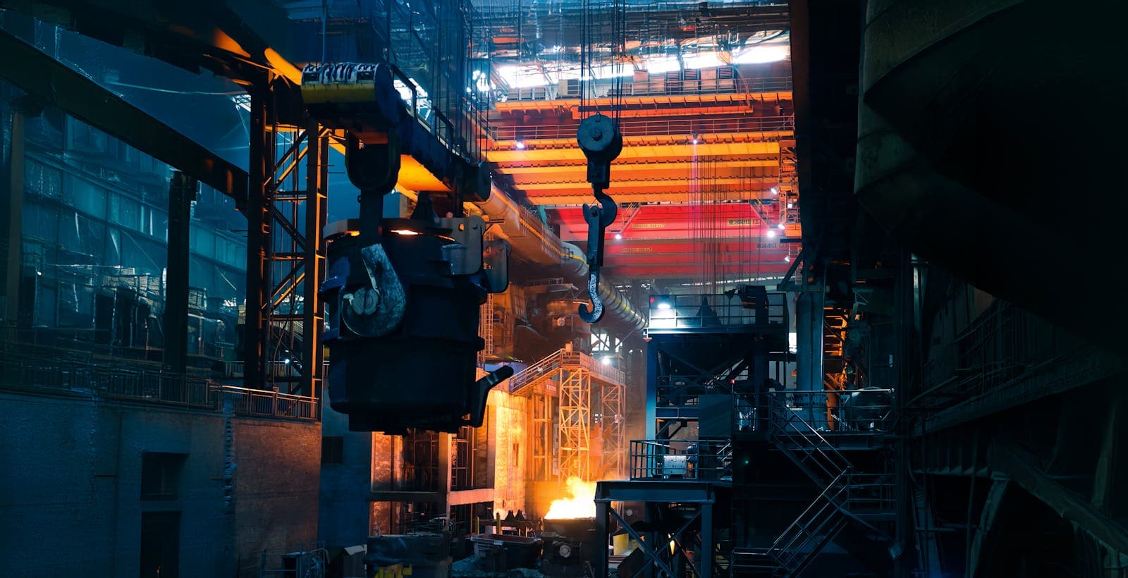 Inside a bustling steel mill with cranes and molten metal.