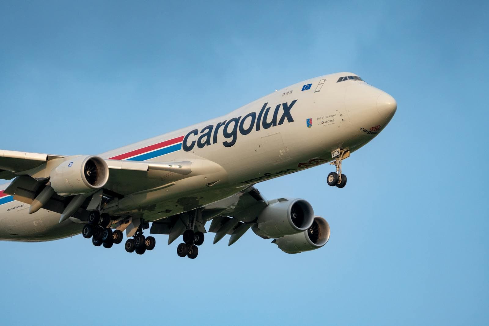 A Cargolux Boeing 747 cargo plane in flight against a clear sky.