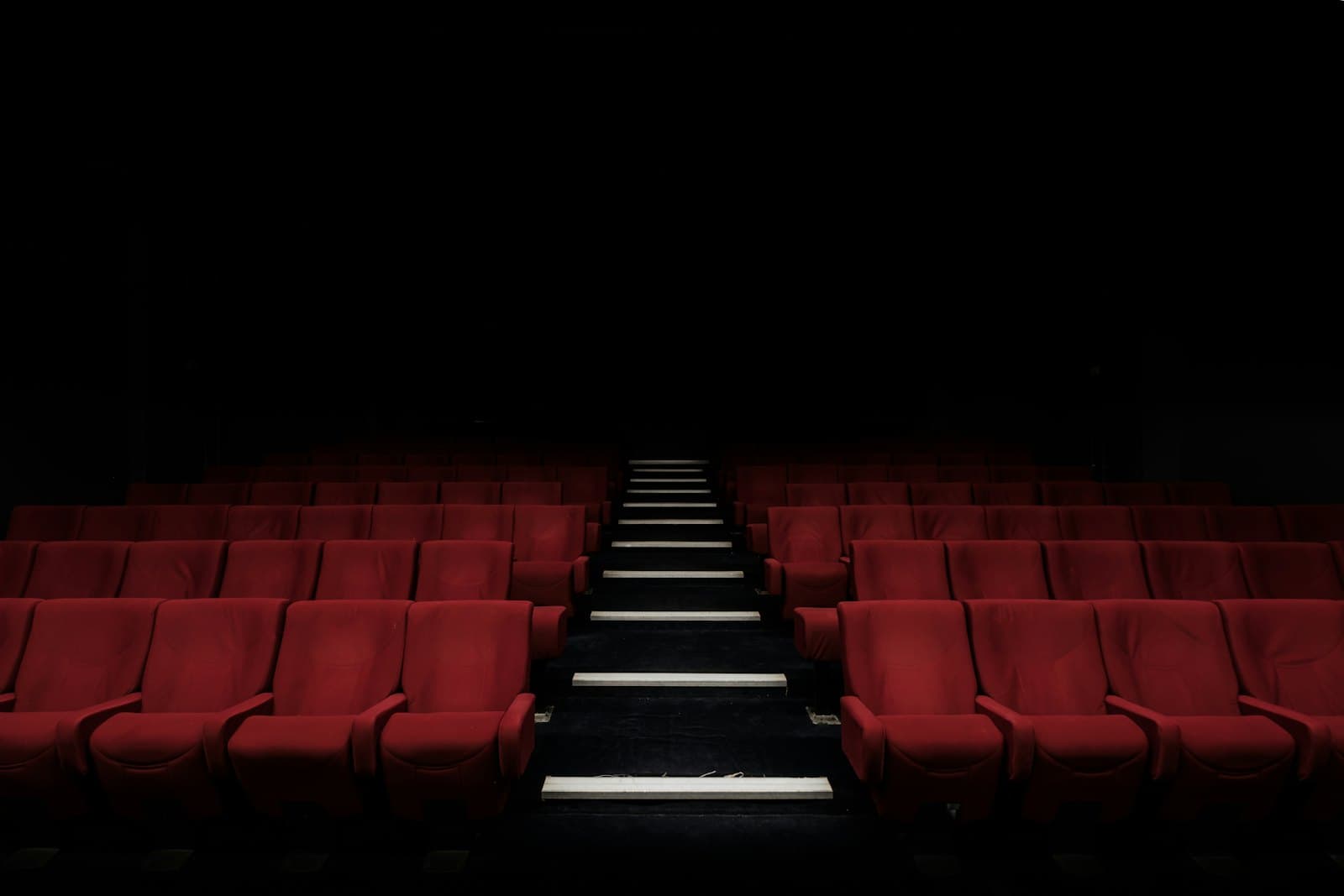 Vintage cinema seats illuminated by warm projector light.