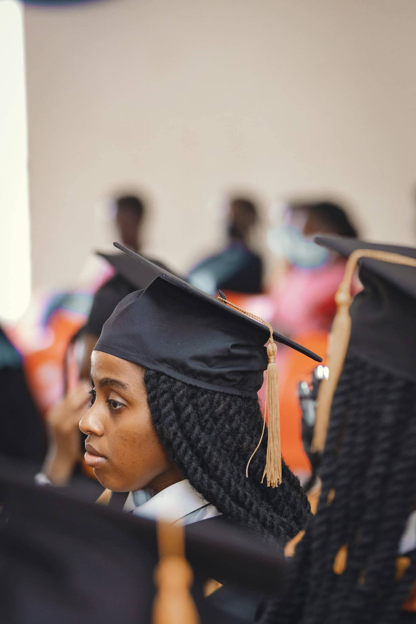 African graduate in cap and gown holding a diploma.